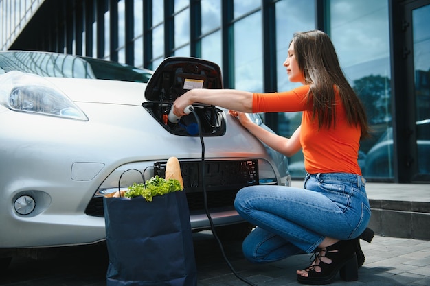 Donna che carica l'auto elettrica alla stazione di gas elettrica