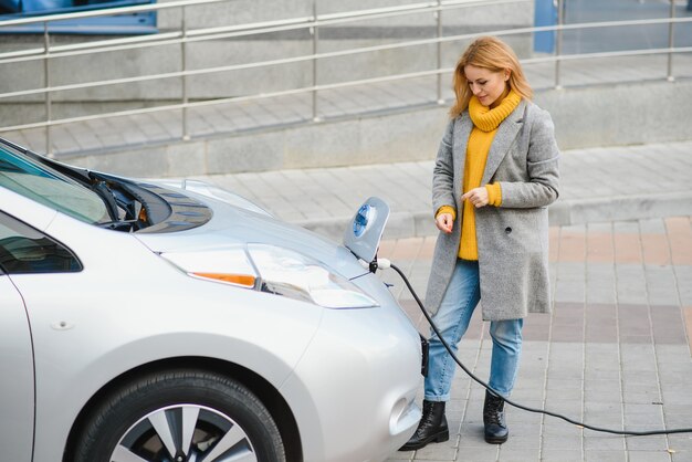 Woman charging electro car at the electric gas station