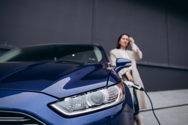 Woman charging electro car at the electric gas station