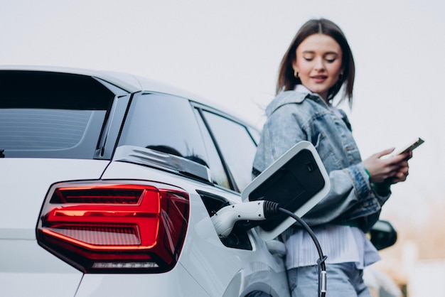 Woman charging her electric car with charging pistol