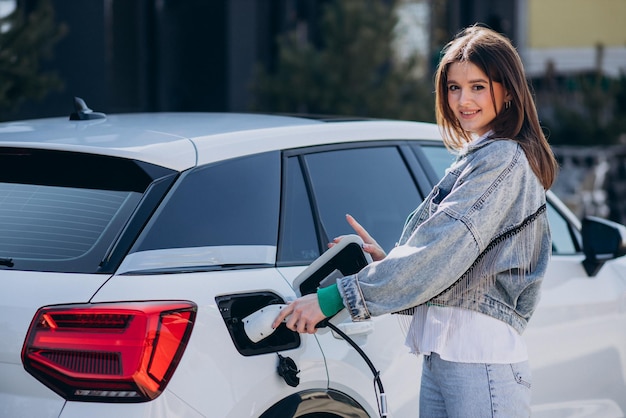 Donna che carica la sua auto elettrica con la pistola di ricarica