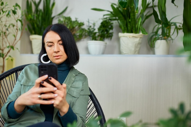 Woman chatting using smartphone sitting on armchair at home