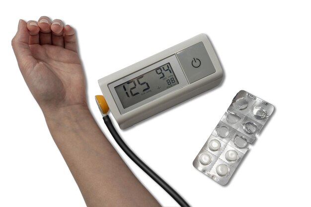 Фото Женщина проверяет артериальное давление цифровой монитор артериального давления и упаковка таблеток на белом фоне