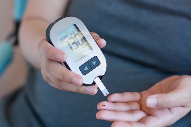 Woman checking blood sugar level with glucometer