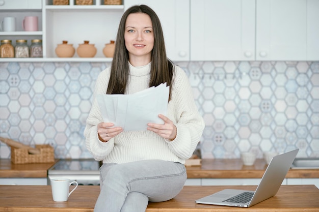 Woman checking financial documents in her kitchen