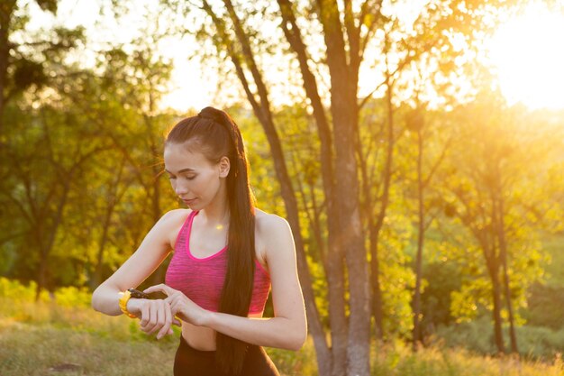 Woman checking fitness and health tracking wearable device in the park