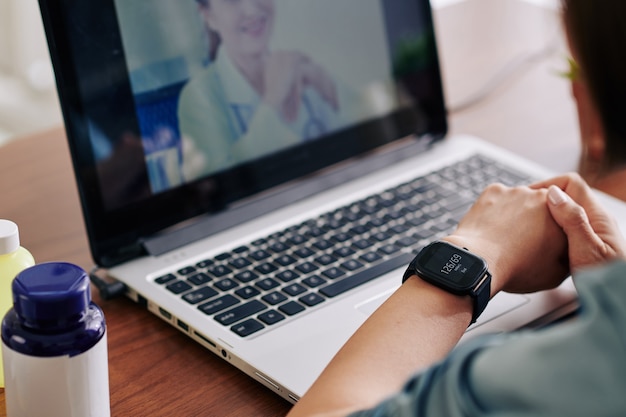 Woman checking her blood pressure via application on smartwatch and telling it to virtual doctor