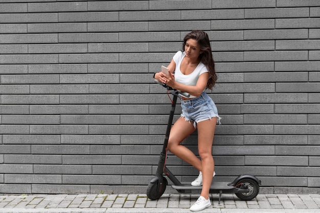 Foto donna che controlla il suo smartphone mentre su scooter elettrico