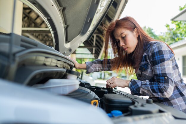 Foto donna che controlla il livello dell'olio in un'auto