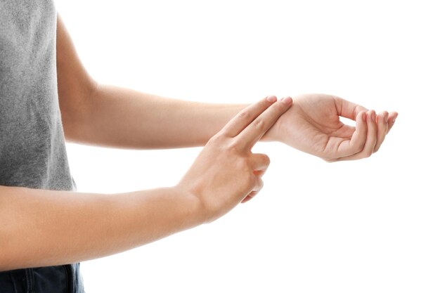 Woman checking pulse on wrist against white background closeup