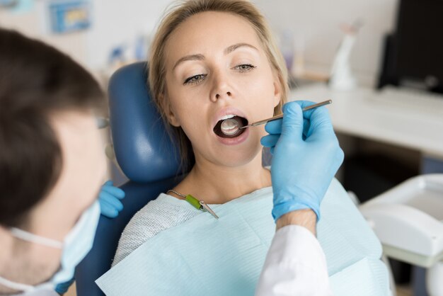 Woman checking teeth of pretty client