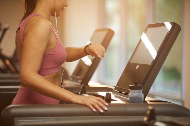 Woman Checking Watch while Running on Treadmill