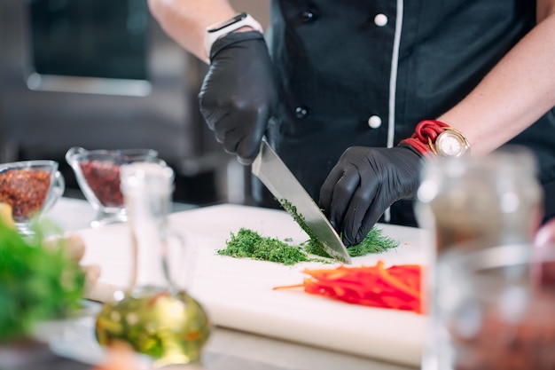 A Woman Chef cuts vegetables in the kitchen in a restaurant