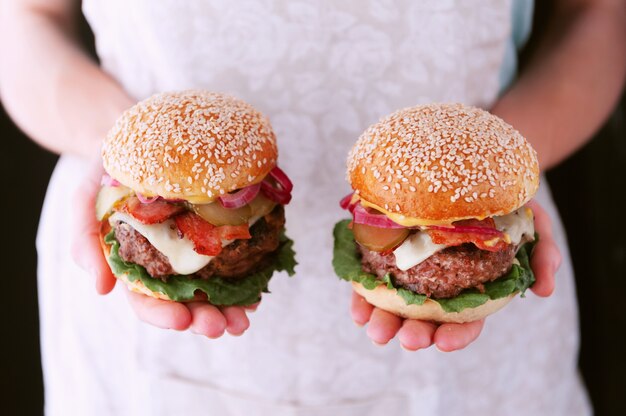 woman chef holding a cooked her delicious and juicy homemade burger in a rustic style with a big chop of beef