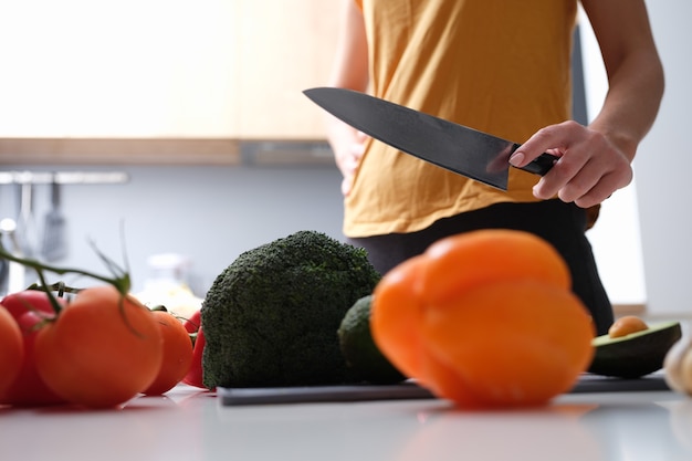 Woman chef holding kitchen cutter for cutting vegetables closeup