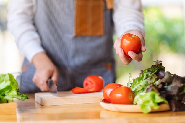 A woman chef holding and picking a fresh tomato from a vegetables tray on the table