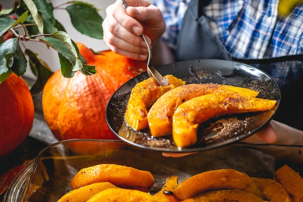 Женщина-повар держит кусочки запеченной апельсиновой тыквы с медом и корицей