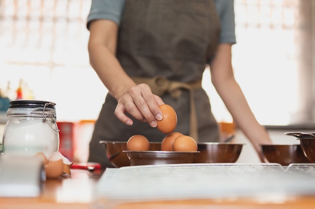 Woman chef pick up fresh raw egg preparing ingredient for making healthy cuisine