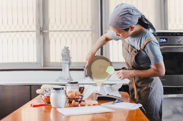 Woman chef pouring cake mixture into a cake tin