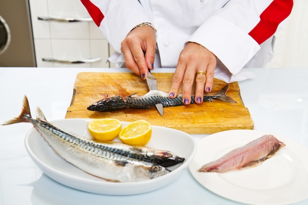 Photo woman chef preparing fillet of mackerel