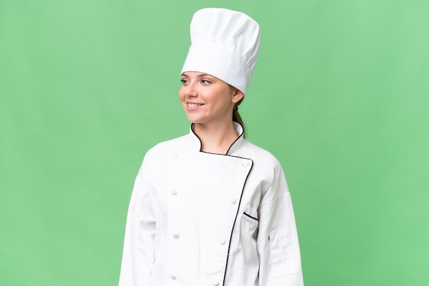 A woman in a chef's hat stands in front of a green screen