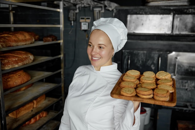 Photo woman chef with tray of appetite delicious pastry standing at bakery kitchen