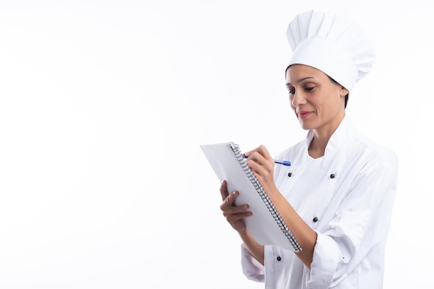 Foto cuoco unico della donna che scrive nel suo taccuino isolato su priorità bassa bianca con lo spazio della copia