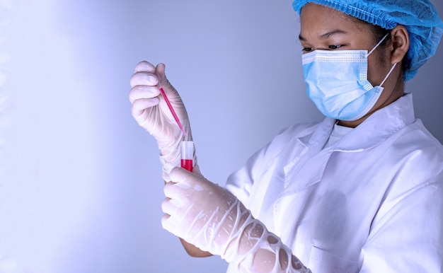 Woman chemist holds flask with red liquid in her hands in\
chemical laboratory. products quality control concept.