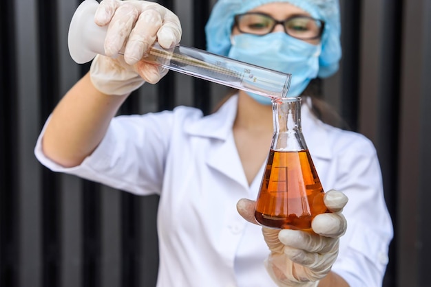 Woman chemist making experiment with two flasks. Science and chemistry concept