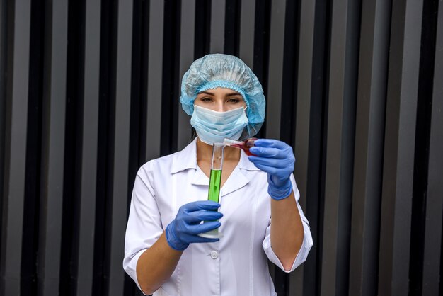 Woman chemist with test tubes and protective uniform making experiment with two substance