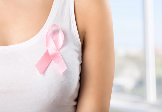 Woman chest with pink badge to support breast cancer cause,