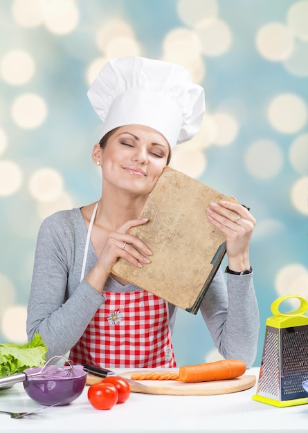 Woman in chief's hat with old grandmother's cookbook