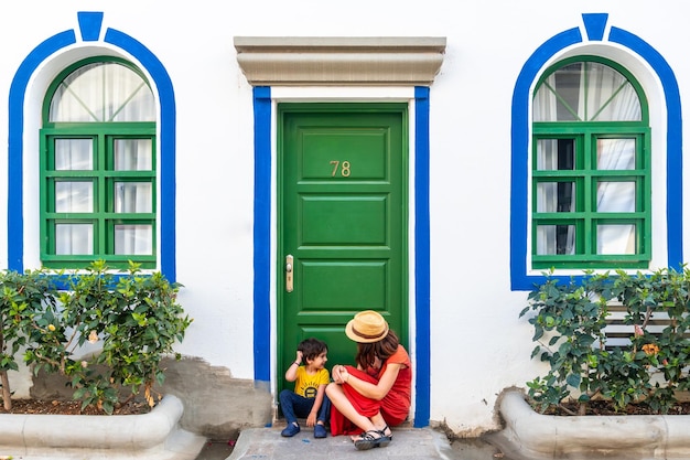 A woman and a child are sitting on the steps of a building with a green door