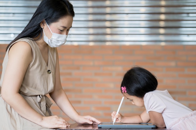 A woman and a child are working on a tablet.