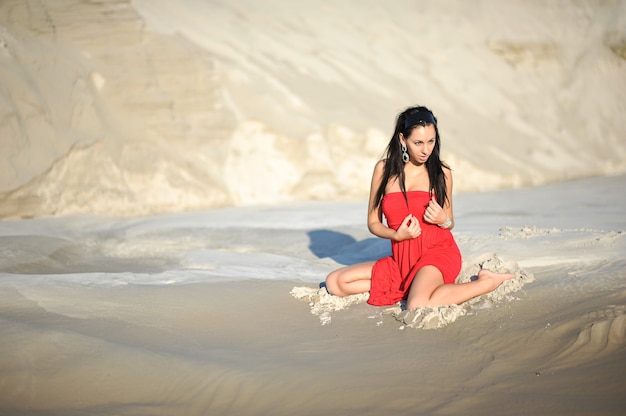 woman chilling on the sand in red dress