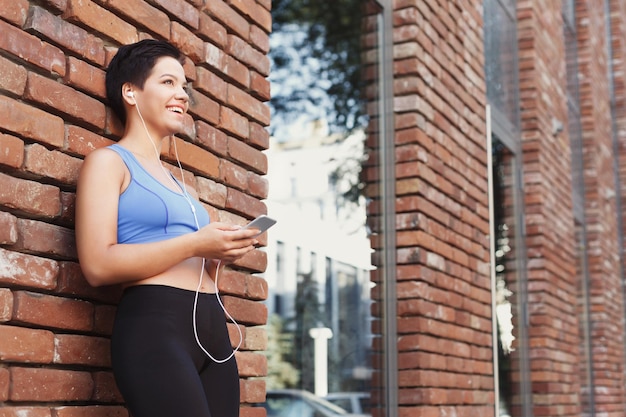 Woman choose music to listen in her mobile phone during jogging
in city, copy space