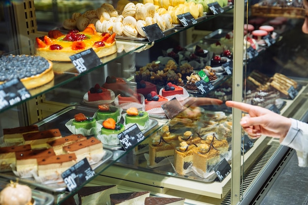 Woman choose sweets in store deserts shop