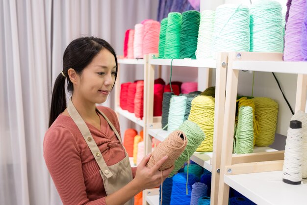 Woman choose the thread for making carpet with the tufting gun