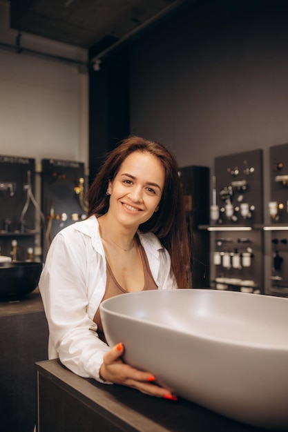 Woman chooses a ceramic sink in a hardware supermarket