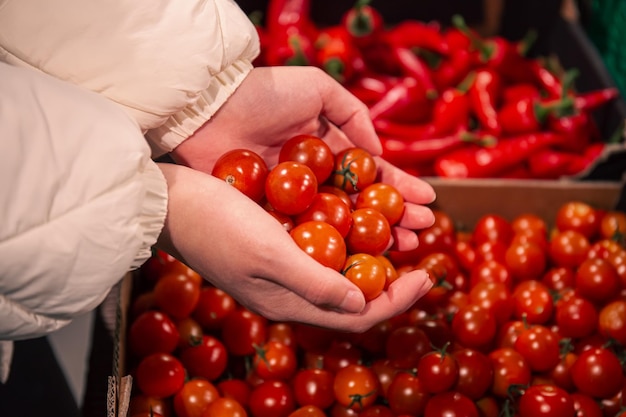 A woman chooses cherry tomatoes in a grocery store closeup