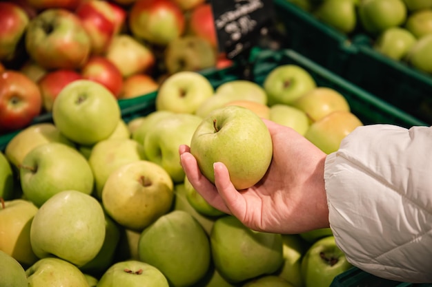 女性は、スーパー マーケットの有機および自然な果物で青リンゴを選択します