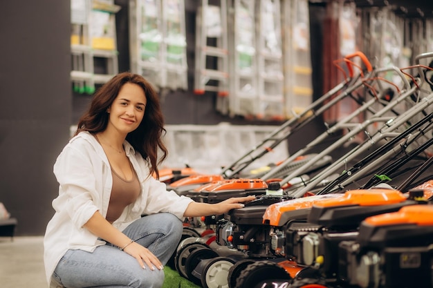 Photo a woman chooses a lawnmower in a home improvement store