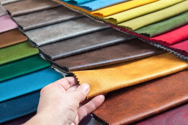 Woman chooses samples of colored fabric on table close up