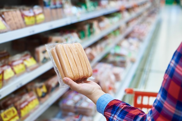 Photo woman chooses sausages in the store