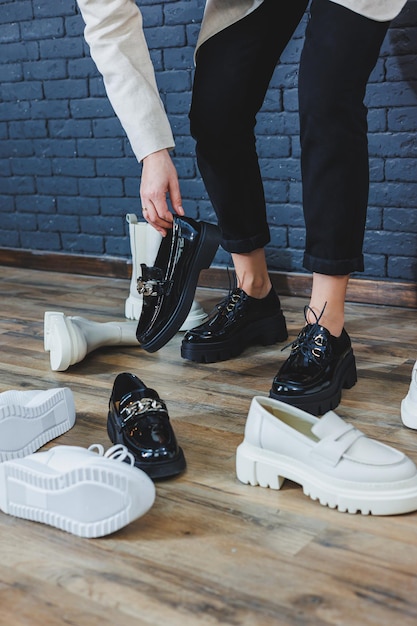 Photo a woman chooses shoes against a brick wall several pairs of women's leather shoes