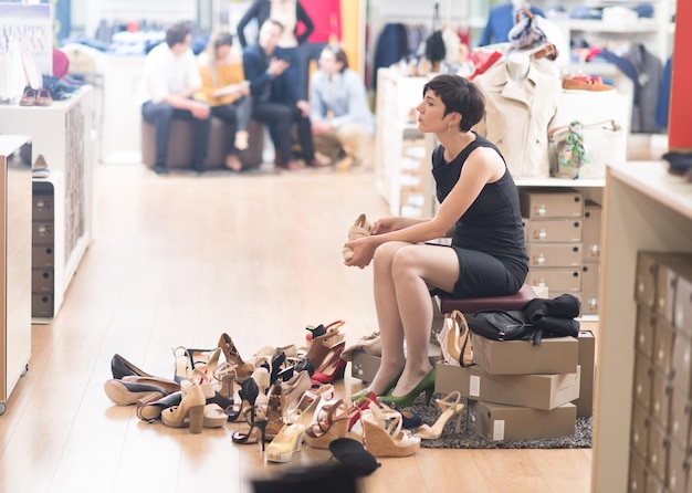 Woman Chooses  Shoes At Fashionable Shop