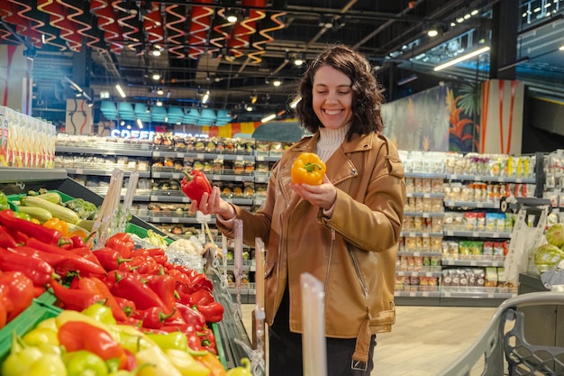 A woman chooses sweet peppers in a supermarket