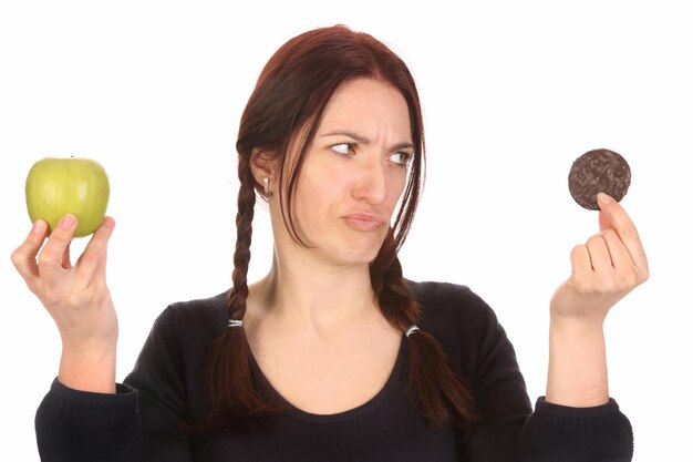 Photo woman choosing between chocolate cookies and apple