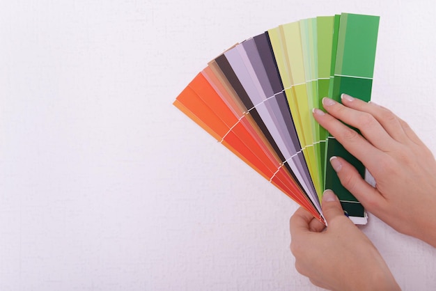 Woman choosing color for wall from swatches in room