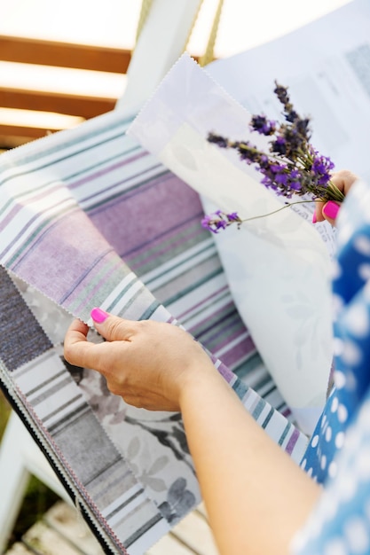 Foto donna che sceglie il tessuto per le nuove tende la ragazza tiene in mano un bouquet di lavanda fiori di lavanda profumati catalogo di tessuti